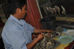 manang shucking the steamed fresh oysters